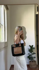 Bolso tote negro con textura símil cuero de cocodrilo, bolsillo externo color beige y asas marrones.