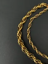 Collar de cadena con eslabones trenzados de diseño robusto y versátil. Fabricado en acero inoxidable con recubrimiento en tono dorado.