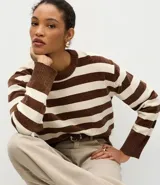 Suéter de cuello redondo confeccionado en tejido de chenille con diseño de rayas horizontales en tonos marrón y crema. Presenta un corte regular, mangas largas y terminaciones acanaladas en puños, cuello y ruedo.