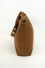 Bolso tipo shopper de gamuza marrón, con asa de hombro ajustable decorada con ojales metálicos plateados y hebilla lateral.
