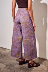 Jean wide leg de tiro alto en color lila, con un llamativo estampado de hojas grandes en tonos marrones sobre un sutil fondo de cuadros.
