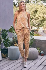 Pantalón de tiro alto con estampado paisley en tonos maíz y tierra, confeccionado en tejido fluido. Presenta cintura elástica con cordón ajustable y bolsillos laterales.