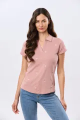 Remera polo de algodón color beige con mangas cortas, escote en V y cuello camisero. Presenta delicados mini bordados florales distribuidos en toda la prenda.
