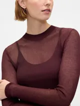 Buzo de tejido fino y semitransparente con cuello redondo y mangas largas, diseñado con una capa superpuesta estilo musculosa de punto acanalado.