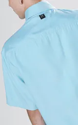 Camisa de manga corta, color celeste, con cuello camisero y calce relajado (relax fit). Presenta cuatro bolsillos cargo frontales con tapa y cierre frontal de botones.