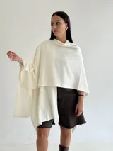 Ruana de tejido de punto trenzado en color crudo, con diseño abierto, corte holgado y mangas amplias tipo kimono.