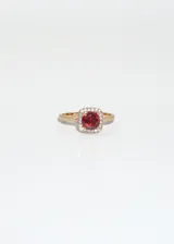 Anillo dorado con zirconia roja cuadrada rodeada de pequeñas zirconias blancas.