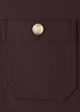 Pantalón de vestir marrón oscuro, de tiro medio y corte recto, con bolsillos frontales tipo parche decorados con botones metálicos dorados.