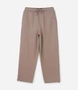 Pantalón de corte baggy confeccionado en tejido de algodón con felpa, color beige. Presenta cintura elástica con cordón ajustable, bolsillos laterales y bajo ajustable mediante elástico.