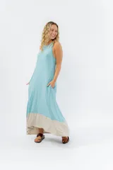 Vestido largo celeste con corte holgado, escote redondo y sisas amplias. Presenta un ruedo con recorte en color arena y bolsillos laterales.