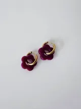 Aros de acero quirúrgico dorados con dijes colgantes en forma de flor de acrílico color bordó.