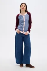Cardigan de punto con diseño color block, presenta cuerpo en color celeste, mangas en color bordó y detalles de botones y bordes en color rosado. Posee cuello redondo y mangas largas.