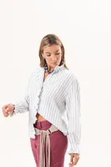 Camisa de manga larga con diseño a rayas celestes y blancas, cuello alto y detalle de volados en la cartera frontal y los puños.