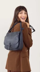 Bandolera morral color bordó, con tapa y broche, bolsillo principal, bolsillos internos organizadores y cierre trasero.