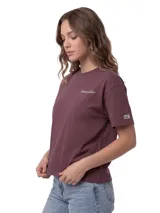 Remera de corte boxy y cuello redondo, confeccionada en algodón color violeta. Presenta un gráfico bordado con el logo de la marca en el pecho y un parche tejido distintivo en la manga.