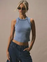 Top sin mangas de calce ajustado, color celeste pastel, con cuello redondo alto y costuras decorativas en contraste que resaltan el diseño. Presenta un largo cropped y está confeccionado en tela elastizada.