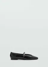 Zapato tipo bailarina de efecto charol color negro, con punta redonda y tira fina en el empeine que cuenta con una hebilla decorativa efecto joya.