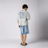 Camisa de manga corta color marfil, corte boxy, con cuello camisero, cierre frontal de botones y pequeño bordado marrón en el pecho con las siglas VCP.
