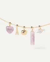 Dije colgante dorado con forma de corazón atravesado por una flecha, con incrustaciones de circonitas blancas.