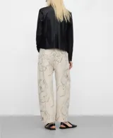 Pantalón barrel fit de denim de algodón orgánico y reciclado, con diseño estampado floral de trazos finos en tonos grises y oscuros sobre base beige. Presenta tiro medio, trabillas para cinturón, bolsillos y perneras redondeadas con costura lateral adelantada.