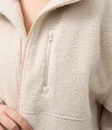 Campera deportiva de sherpa color beige, con cuello alto, cierre frontal completo y bolsillo con cierre en el pecho. Presenta un corte boxy holgado, mangas largas y acabado de textura suave.