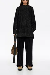 Sweater de punto negro con efecto tweed o neps en color dorado/amarillo claro, cuello alto tipo caja y mangas largas. Corte recto y holgado.