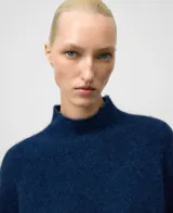 Sweater de punto en color tostado con cuello chimenea y mangas raglán, confeccionado en una mezcla de lana merino y alpaca que le otorga una textura suave y abrigada.