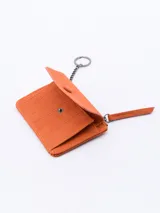 Billetera plateada con textura símil piel de cocodrilo, cierre de cremallera superior y solapa frontal con botón a presión.