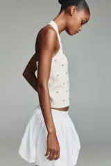 Top de punto negro con cuello halter y escote redondo, decorado con tachas metálicas plateadas distribuidas por toda la prenda.