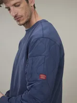 Sweater verde militar de cuello redondo y manga larga con detalle de bolsillo con solapa en la manga izquierda.