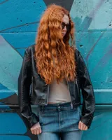 Campera de cuero sintético negro estilo motero con cuello mao, cierre frontal, bolsillos con cierre y detalles de tachas en hombros y mangas.