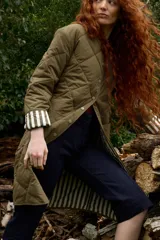 Campera reversible de corte largo, con un lado acolchado en diseño de rombos y el otro lado con estampado de rayas. Cuenta con cierre frontal de botones a presión y bolsillos laterales.