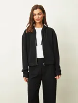 Campera negra con capucha, cierre frontal, mangas largas con puños elásticos y bolsillos laterales.