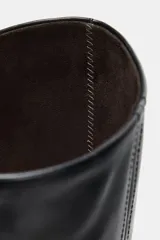 Bota alta de piel color negro, con caña alta, detalles de pespuntes verticales y tacón alto en bloque.