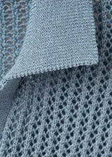 Chaleco de punto celeste, con detalles bordados calados, cuello polo y diseño recto sin mangas.