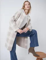 Chaqueta de tejido suave con estampado a cuadros en tonos beige y blanco, cuello con solapa y cierre de botón frontal. Incluye bolsillos delanteros.