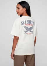 Remera de manga corta color blanco con estampa gráfica en la espalda que incluye el texto Sea Breeze Fish Market y un diseño de peces cruzados.
