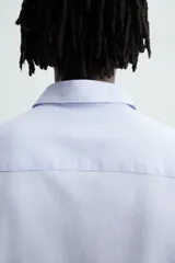 Camisa de corte regular fit en color celeste, con cuello italiano, manga larga con puños abotonados y cierre frontal de botones.