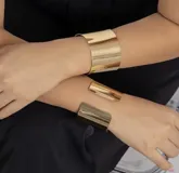 Brazalete ancho de metal dorado, rígido y abierto.