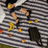 Zapato de cuero vacuno color gris topo, con talón descubierto y pulsera con hebilla. Tiene taco de madera forrado en cuero y suela de goma. La horma es de punta cuadrada, ancha y cómoda.