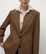 Blazer femenino de corte regular confeccionado en polivelour con textura de espiga. Presenta solapa clásica, mangas largas, cierre frontal con botones y bolsillos funcionales.