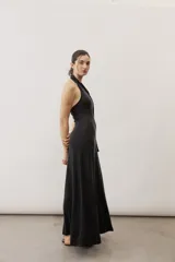 Vestido largo negro de corte al cuerpo con cuello halter y detalle de hebilla metálica dorada en el hombro con tira drapeada.