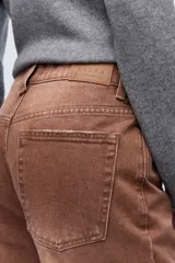 Jean marrón de tiro alto, con pierna levemente acampanada y cierre con botones metálicos.