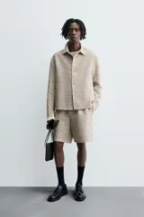 Sobrecamisa de hombre con corte relajado, confeccionada en tejido texturizado jaspeado en tonos beige y negro. Presenta cuello solapa, manga larga con puño de botón y cierre frontal de botonadura.