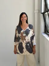 Sweater de punto con diseño estampado tipo animal print en tonos negro, marrón y beige. Presenta cuello en V, mangas tres cuartos con dobladillo y un corte holgado.