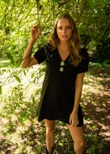 Vestido corto color blanco hueso, de lino con mezcla, corte evasé, cuello en V y botones de nácar.