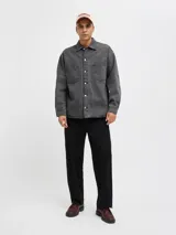 Camisa de denim negra de manga larga con cuello clásico y cierre con botones. Diseño amplio con bolsillos en el pecho.