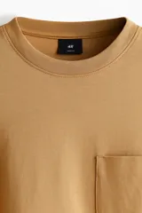 Remera de manga larga en punto pesado de algodón color camel, con cuello redondo ribeteado acanalado, hombros caídos, bolsillo superior abierto y bajo recto. Corte holgado.