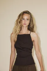 Top color fucsia de escote recto y tirantes finos, con detalle de pliegues y espalda descubierta. Cierre con lazadas en la espalda.