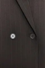 Blazer oversize de corte recto con estampado de raya diplomática. Presenta cuello con solapa, cierre frontal cruzado con botones, hombros caídos y bolsillos delanteros con vivo.